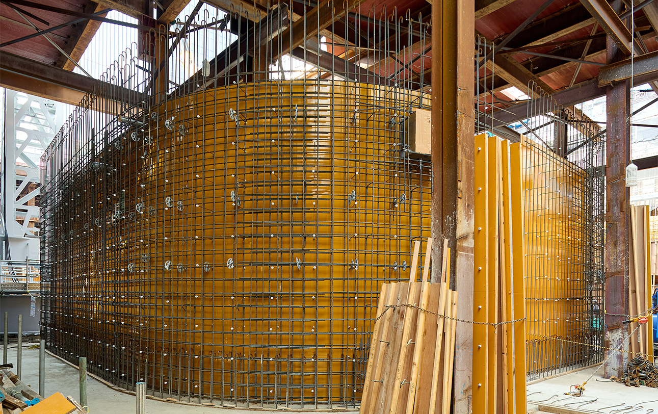 Wall of the ramp to the underground parking area, with reinforcing steel bars precisely arranged along the curved surface.